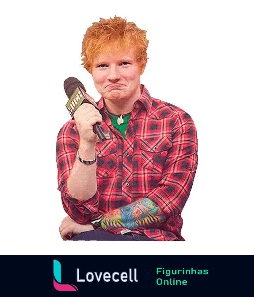 Ed Sheeran de cabelo ruivo fazendo careta engraçada e segurando microfone da MTV, vestido com camisa xadrez vermelha e tatuagens no braço