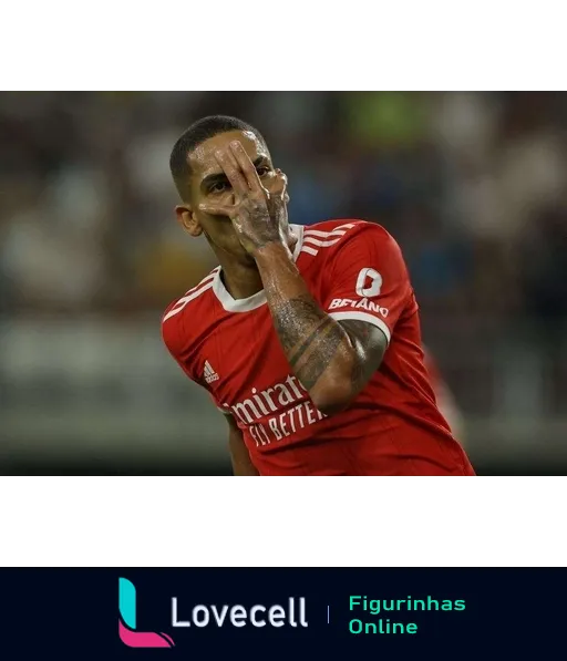 Jogador do Benfica comemorando gol com camisa vermelha e gesto de felicidade e provocação com a mão no rosto