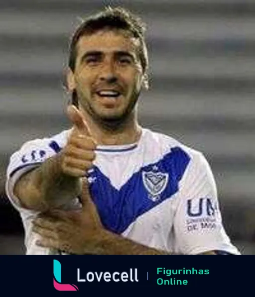 Jogador do Vélez Sarsfield comemorando com polegar para cima e sorrindo, usando uniforme branco e azul