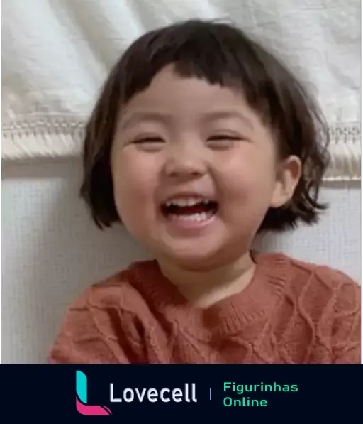 Criança pequena sorrindo alegremente, usando blusa laranja, com cabelos curtos e expressão de felicidade e pureza