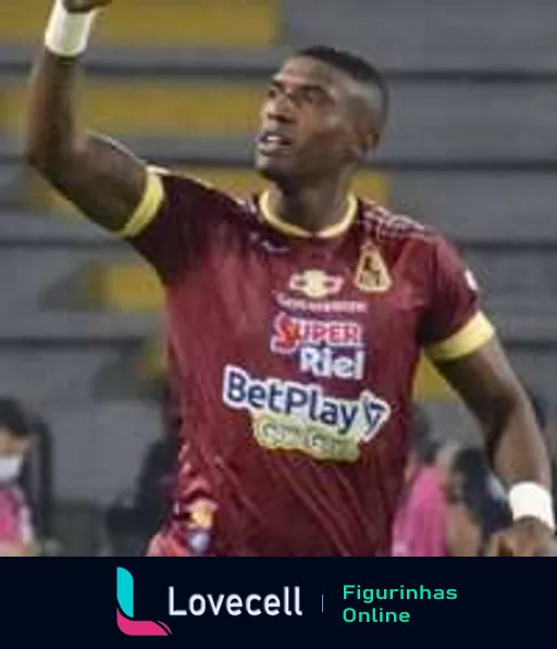 Jogador do Deportes Tolima comemorando em campo com uniforme vinho e amarelo com logos BetPlay e Super Riel