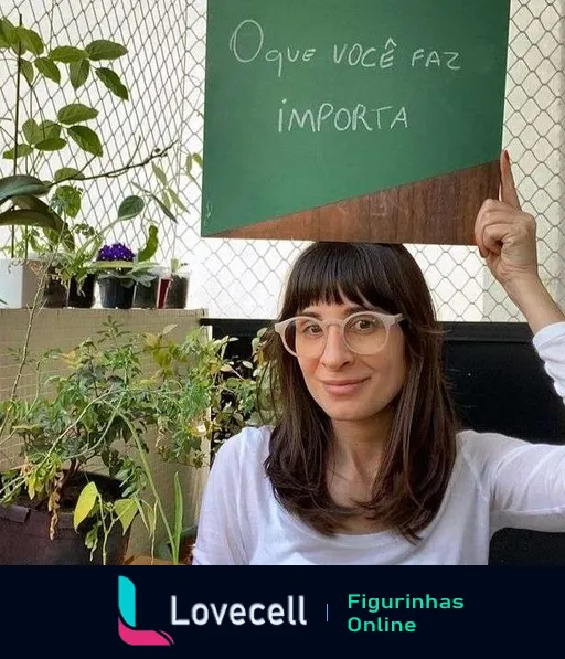 Mulher com óculos e cabelos curtos sorrindo e segurando uma placa com a frase 'O que você faz importa' em um ambiente interno com plantas ao fundo