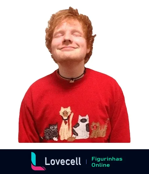 Ed Sheeran sorrindo com suéter vermelho com decoração de gatos