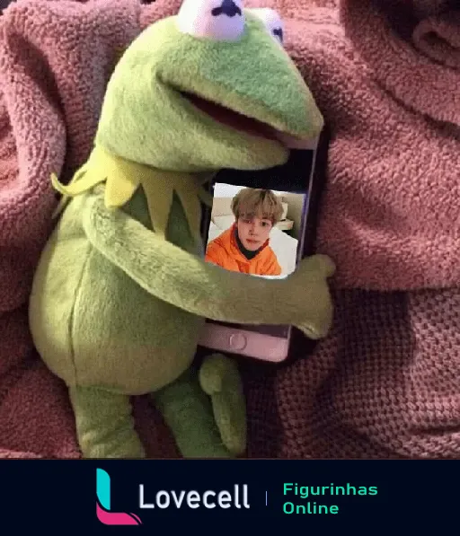 Kermit, o sapo, abraçando um celular com uma foto de um integrante do BTS na tela, mostrando um humor triste.