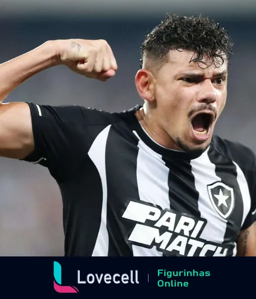 Jogador do Botafogo comemorando intensamente em campo com punho cerrado e expressão emocionada, vestindo uniforme preto e branco com patrocínio Pari Match