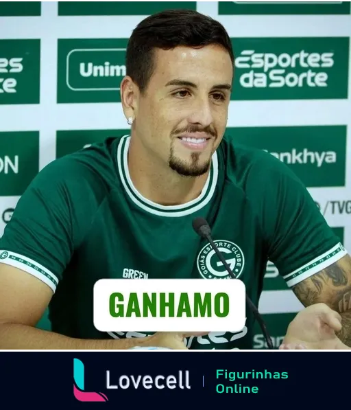 Figurinha de jogador do Goiás sorrindo em entrevista coletiva, vestindo camisa verde do clube, com a palavra 'GANHAMO' destacada