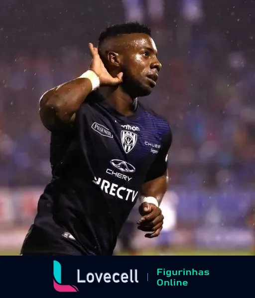 Jogador do Independiente del Valle comemorando gol em campo noturno sob chuva, vestindo camisa preta e com mão na orelha