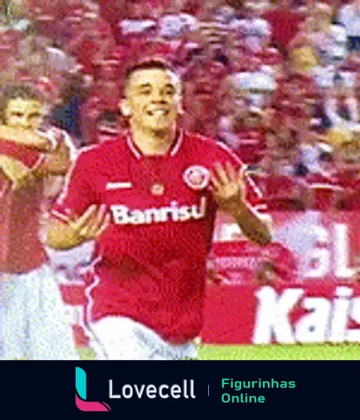 Jogador do Internacional comemorando no estádio Beira-Rio, vestido com uniforme vermelho com patrocínios da Banrisul e Fábrica de Craques, aplaudindo e sorrindo.