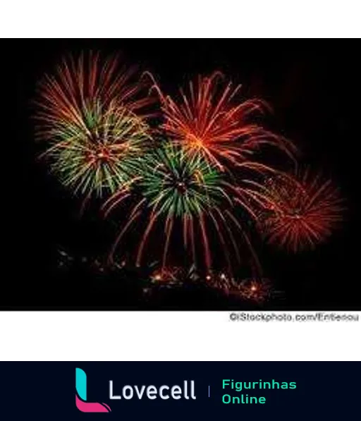 Espetáculo pirotécnico com fogos de artifício em vermelho, verde e laranja iluminando o céu noturno, formando linhas brilhantes e diversas formas.