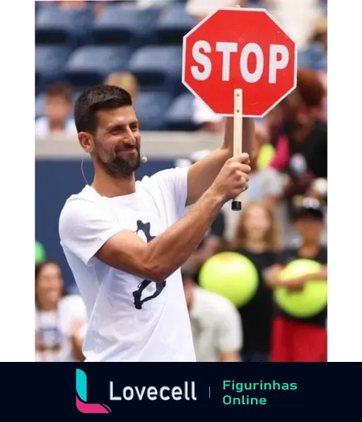 Novak Djokovic sorrindo e segurando uma placa de STOP, vestindo camiseta branca em evento de tênis