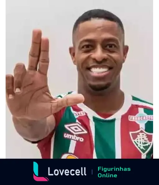 Jogador do Fluminense sorrindo e saudando com a mão, vestindo uniforme verde, grená e branco da Umbro com logo da UPCast