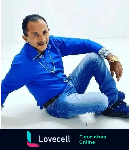 Manoel Gomes, conhecido pelo meme Caneta Azul, posa descontraído no chão, vestindo camisa azul e jeans, com um leve sorriso.