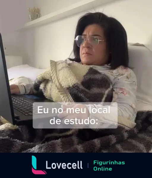 Mulher jovem vestida com roupas de inverno e óculos, envolta em um cobertor, sentada concentrada em frente a um laptop em casa, estudando ou trabalhando