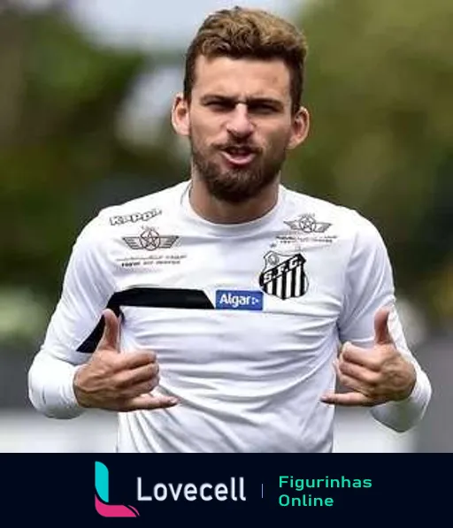 Jogador do Santos vestido com uniforme branco oficial fazendo gesto de positivo com as duas mãos, parecendo motivado e pronto para treino ou partida