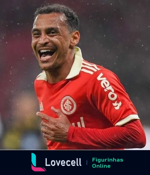 Jogador do Internacional vestindo uniforme vermelho sorrindo e comemorando durante partida sob chuva