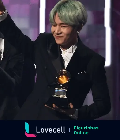 Membro do grupo BTS, em um terno elegante, segurando um troféu Grammy com um sorriso enquanto acena, iIluminado no palco.