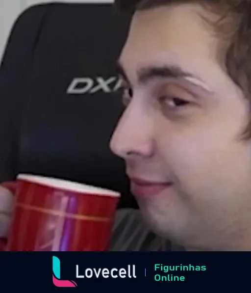 Imagem de Alanzoka segurando uma caneca vermelha e olhando para a câmera com um sorriso de canto. Ao fundo, uma cadeira DXRacer.