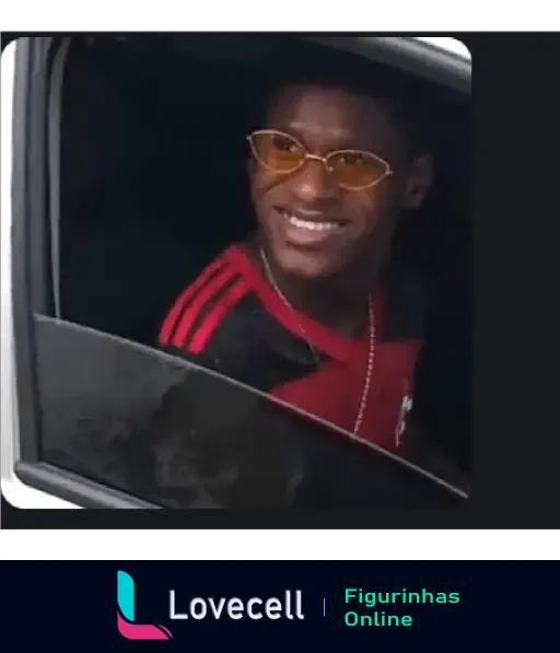 Foto de um homem sorridente com óculos amarelos e uma camisa vermelha vista através da janela de um carro.