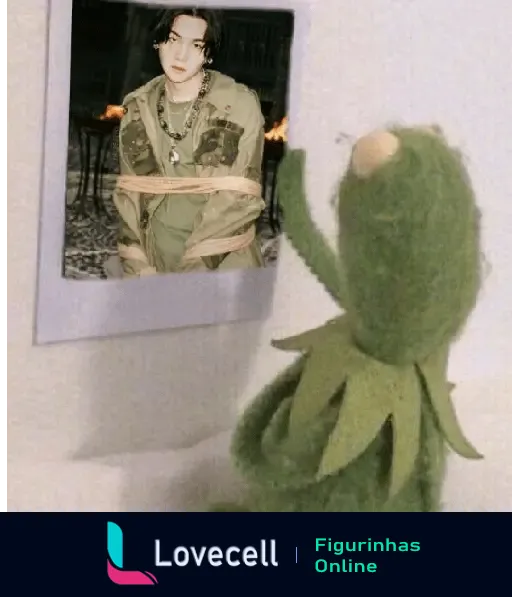 Figurinha de WhatsApp com a imagem do sapo Kermit olhando tristemente para uma foto de um integrante do BTS, expressando saudade.