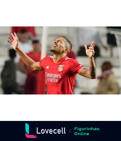 Jogador do Benfica comemorando durante partida de futebol, vestido com uniforme vermelho, levantando as mãos e olhando para o céu em sinal de vitória