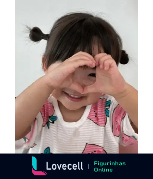 Criança com dois coques no cabelo fazendo sinal de coraçãozinho com as mãos, sorrindo e vestindo uma camiseta de melancias.