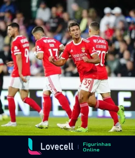 Jogadores do Benfica comemorando no campo, jogador número 39 expressando alegria após gol, com outros atletas ao redor participando da celebração.