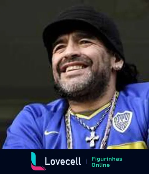 Homem sorridente com cabelos longos e barba em evento esportivo, vestindo camisa do Boca Juniors azul e amarela, boina preta e colar com distintivo prateado