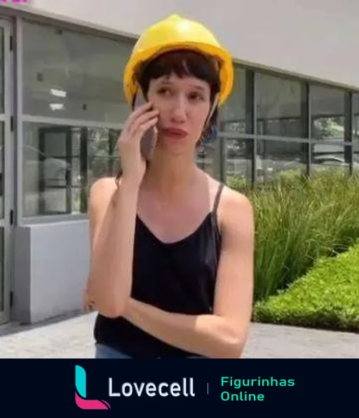 Tina preocupada falando ao telefone com capacete amarelo de segurança em ambiente de construção