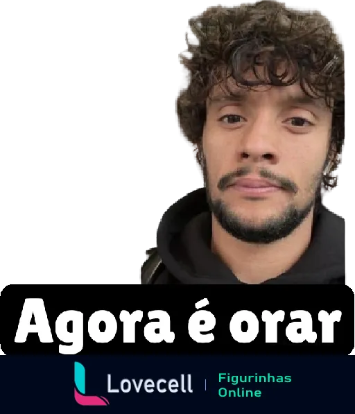 Homem com cabelo cacheado e barba, sério e pensativo, usando blusa preta com capuz, com frase 'Agora é orar' em letras brancas