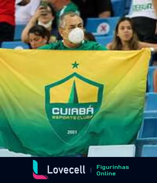 Torcedor do Cuiabá Esporte Clube segurando bandeira verde e amarela com logo do clube, usando máscara facial branca em evento esportivo