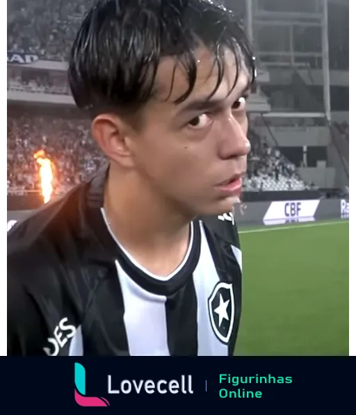 Jogador do Botafogo focado em campo com uniforme durante jogo noturno, cabelo molhado por suor ou garoa