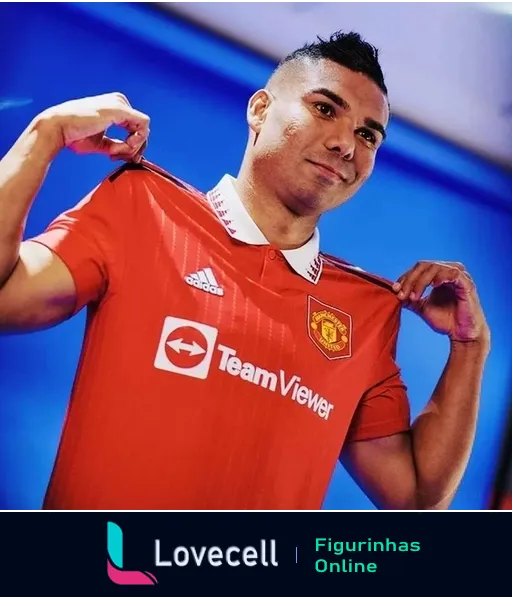 Jogador do Manchester United sorrindo e segurando a gola da camisa vermelha com patrocínios da TeamViewer e adidas