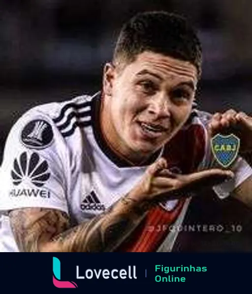 Jogador do River Plate comemorando entusiasmado, segurando escudo do Boca Juniors, vestido com camisa patrocinada pela Huawei e Adidas