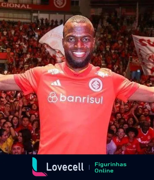 Jogador do Internacional sorridente com uniforme vermelho, patrocínio do Banrisul, celebrando com braços abertos frente a torcedores