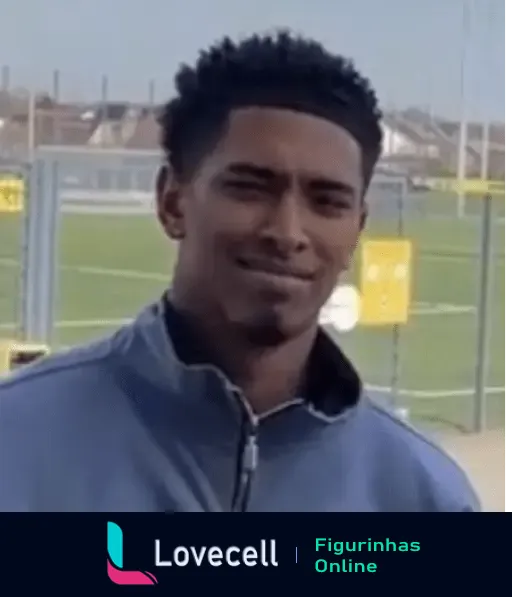 Imagem do Beligol Bellingham, um jovem jogador de futebol, sorrindo levemente em um campo de treinamento ao ar livre.