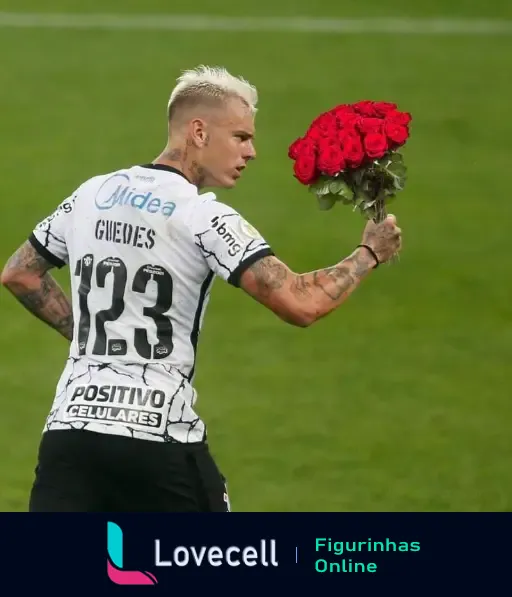 Jogador com cabelo loiro platinado, vestindo camisa 123 com nome 'Guedes', segurando um buquê de rosas vermelhas em campo de futebol.