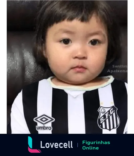 Criança pequena com cabelo preto e olhos expressivos vestindo camisa do Santos FC com logotipos da Umbro