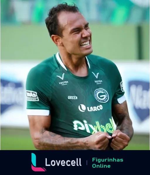 Jogador do Goiás comemorando intensamente em campo, vestindo uniforme verde com logos da Vectra e Dular, expressando emoção com uma expressão que parece dor ou alegria extrema