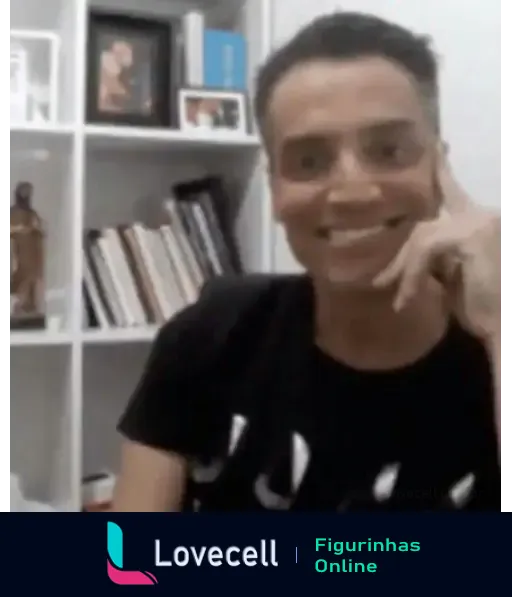 Figurinha de um homem sorrindo com a mão no rosto. Ao fundo, uma estante com livros e objetos decorativos. Parece estar em um ambiente doméstico.