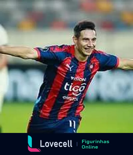 Jogador do Cerro Porteño comemorando com sorriso e braços abertos, vestindo uniforme azul e vinho com patrocínio Tigo